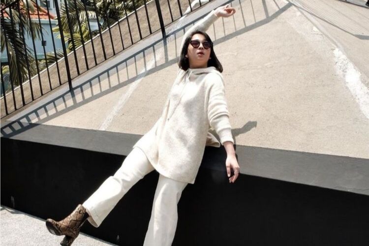 Agatha Pricilla mengenakan setelan putih dan kacamata hitam dengan boots snakeskin